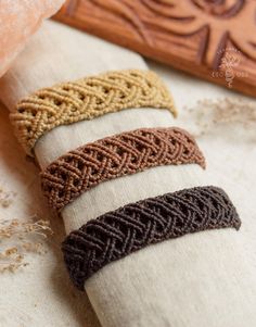 four different colored bracelets sitting on top of a white cloth covered napkin next to a wooden block