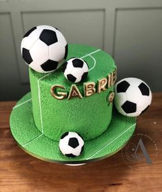 a green cake with three soccer balls on top