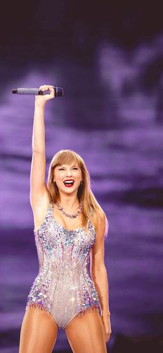 taylor swift performing on stage with her arms in the air