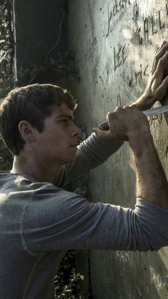 a man writing on the side of a wall with his hand and knife in front of him