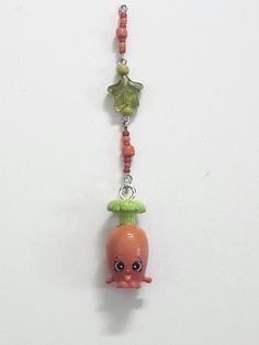 a necklace with an orange and green beaded charm hanging from it's side