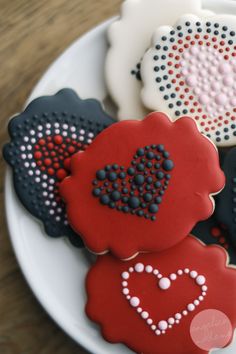 four decorated cookies on a plate with hearts