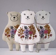 three white bears with flowers on their bodies and the words embroidery + sewing in front of them