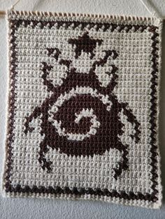 a close up of a crocheted wall hanging with an animal design on it