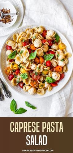 a white plate topped with pasta salad next to silverware and spoons on a table