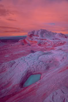 the sky is pink and purple as it sets over an area with some water in it