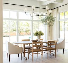 a dining room table with chairs and a vase filled with flowers on top of it