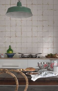 a table with plates and bowls on it in front of a light hanging from the ceiling