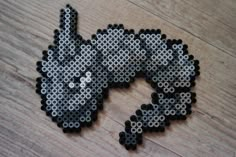 a piece of art made out of legos on a wooden table with the shape of a cat