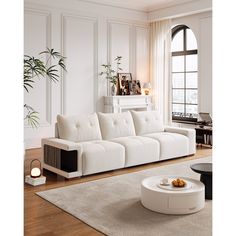 a living room with white furniture and large windows in the back ground, along with a rug on the floor