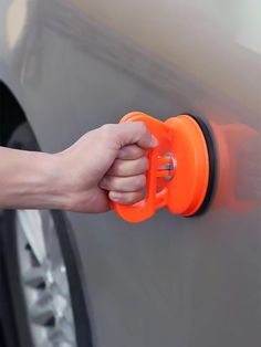 a person is opening the door with an orange handle on a car's side