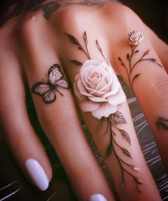 two hands with tattoos on them and one has a white rose, butterfly and leaves