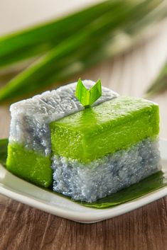 a piece of green cake sitting on top of a white plate next to some green leaves