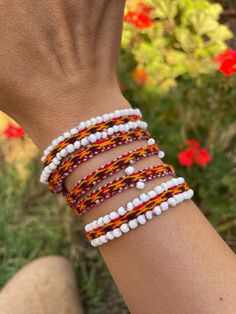 a woman's arm with three different bracelets on it, one is white and the other is red