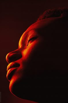 a woman's head with her eyes closed in the dark by an orange light