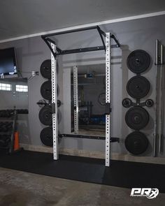 a home gym with squat racks, barbells and television mounted to the wall