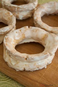 four doughnuts sitting on top of a cutting board with icing around them