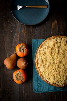 a pie sitting on top of a wooden table next to oranges