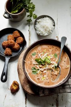 there is a bowl of soup with meatballs and rice on the table next to it