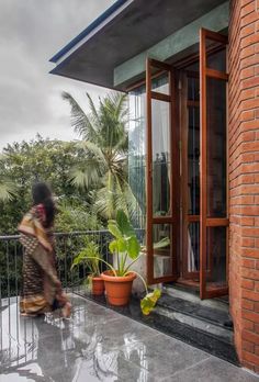 a woman is walking on the balcony with potted plants