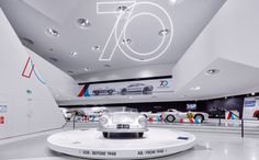 a car showroom with cars on display in the center and an overhead sign that reads 70