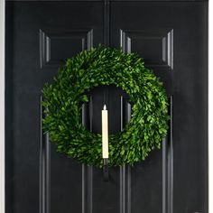 a wreath on the front door with a lit candle