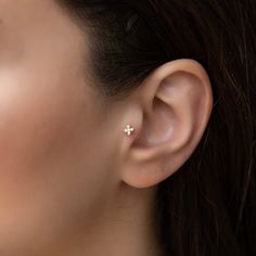 a close up of a person's ear with a small cross on the side