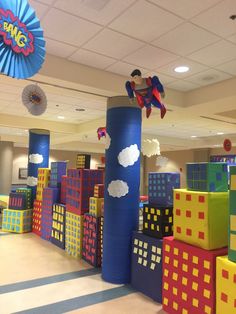 an indoor play area with giant blocks and superman on the top, surrounded by decorations