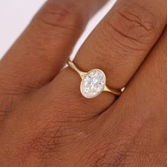 a woman's hand with a gold ring and a white diamond on the band