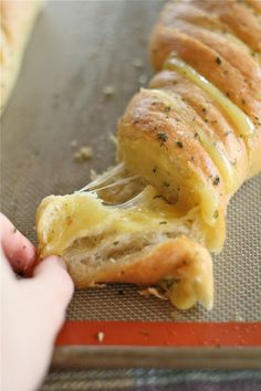 a person is holding a piece of bread with cheese on it and being pulled out