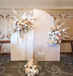 two tall floral arrangements on display in front of a wall