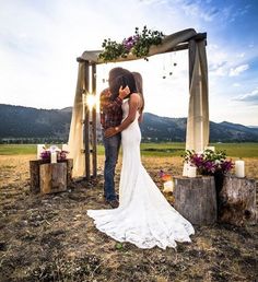 a bride and groom kissing in front of a wooden arch