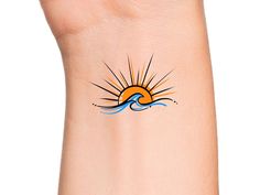 the sun is rising above the water on this wrist tattoo