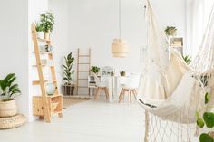 a hammock hanging from the ceiling in a living room with potted plants