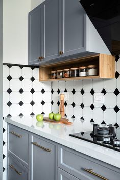 a kitchen with black and white tiles on the backsplash, green apples in front of an oven