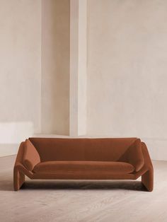 an orange couch sitting on top of a hard wood floor next to a white wall