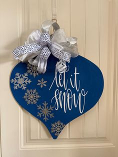 a blue heart shaped door hanger with silver snowflakes and let it snow written on it