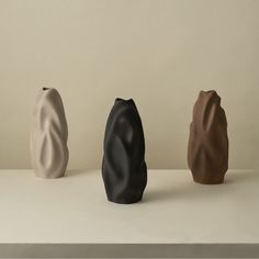 three different colored vases sitting next to each other on a white counter top,