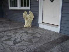 an angel statue sitting in front of a door on the sidewalk next to a house