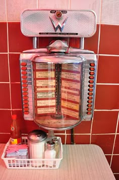 a weird looking machine sitting on top of a table next to a red tiled wall