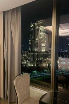 a hotel room with a large window overlooking the city at night, and a chair in front of it