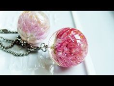 two pink glass balls are attached to a silver ball chain on a white table top