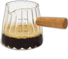 a measuring cup filled with liquid next to a wooden spoon