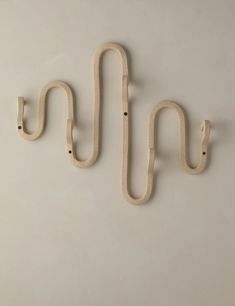 two wooden hooks hang on the wall, one is shaped like a snake's tail