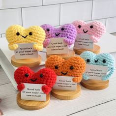 small crocheted hearts are displayed on wooden stands with cards in front of them