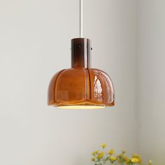 a brown light hanging from a ceiling in a room with yellow flowers on the table