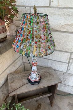 a lamp made out of glass bottles on top of a table next to a potted plant