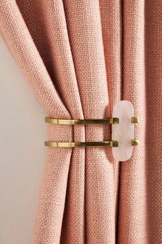 the curtain is closed and there are two gold pins attached to the pink drapes