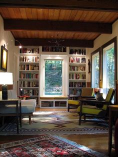 a living room filled with lots of furniture and bookshelves next to a window