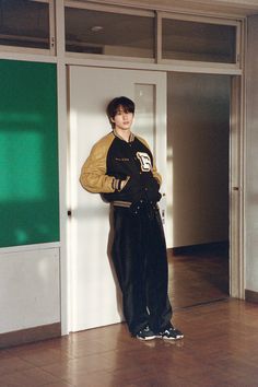 a young man standing in front of an open door with his hands on his hips